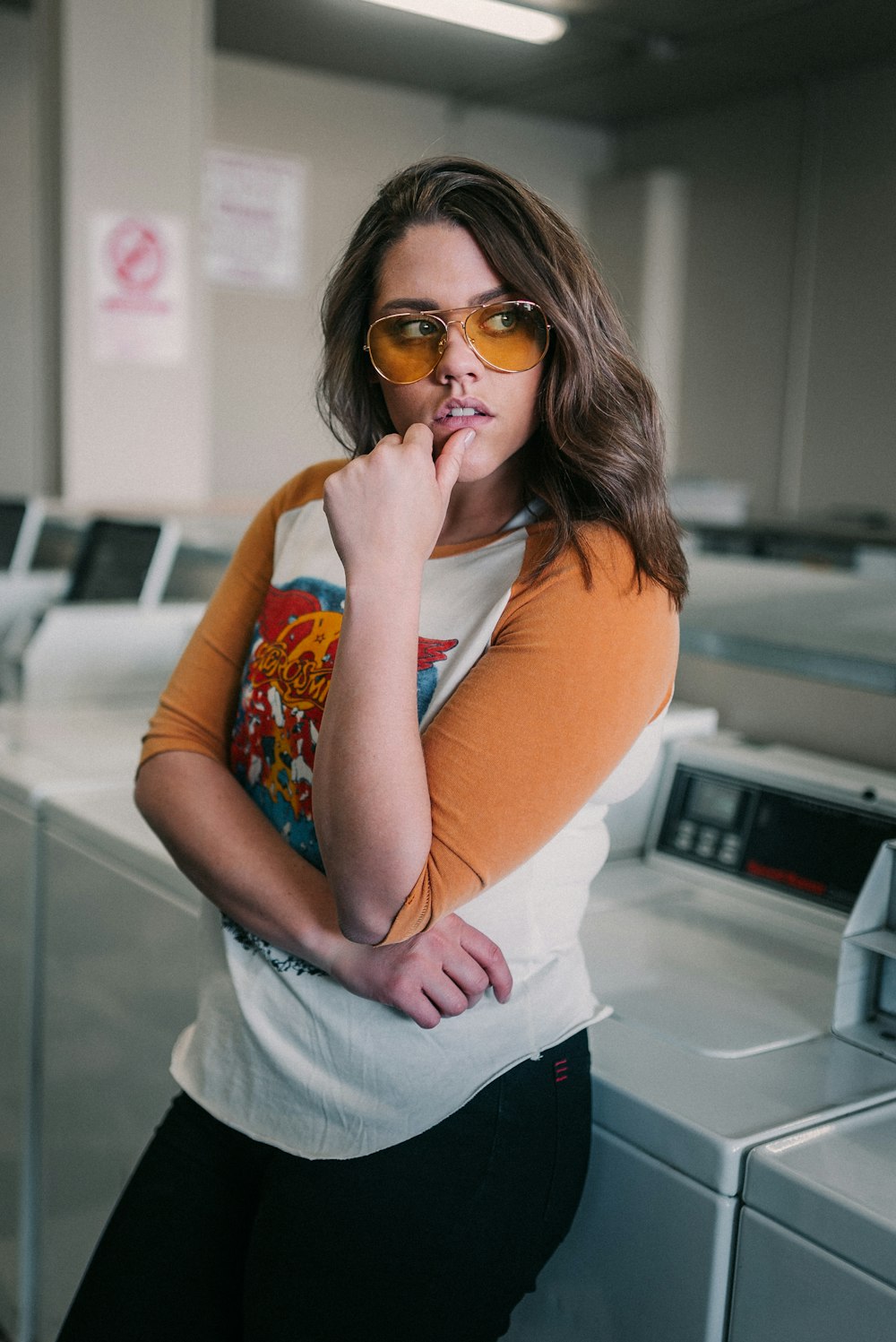 Frau in orangefarbenem Hemd und blauer Jeansshorts mit Sonnenbrille