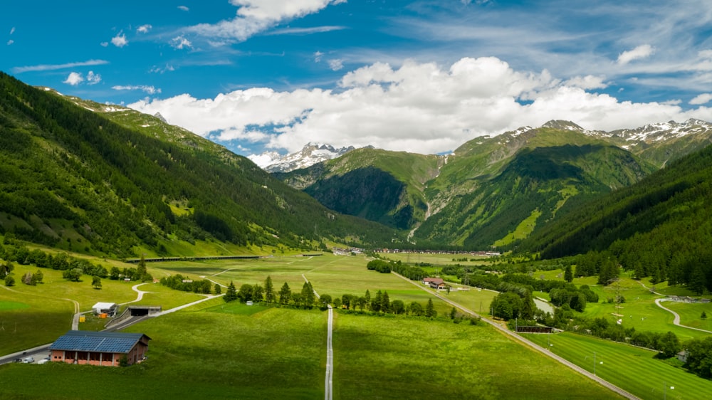 green grass field and mountains under blue sky during daytime