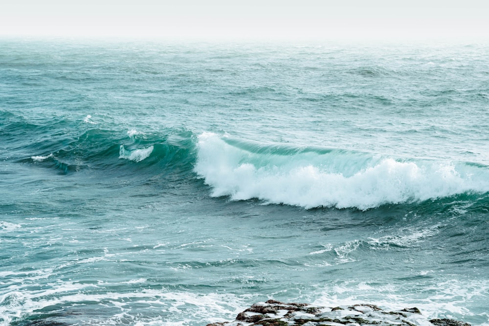 ocean waves crashing on rocky shore during daytime