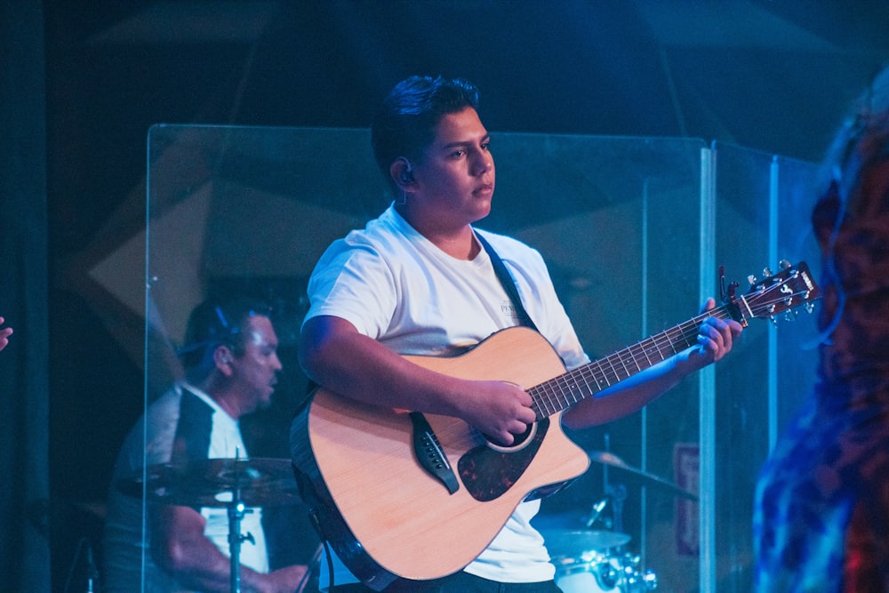 man in white and blue stripe polo shirt playing guitar