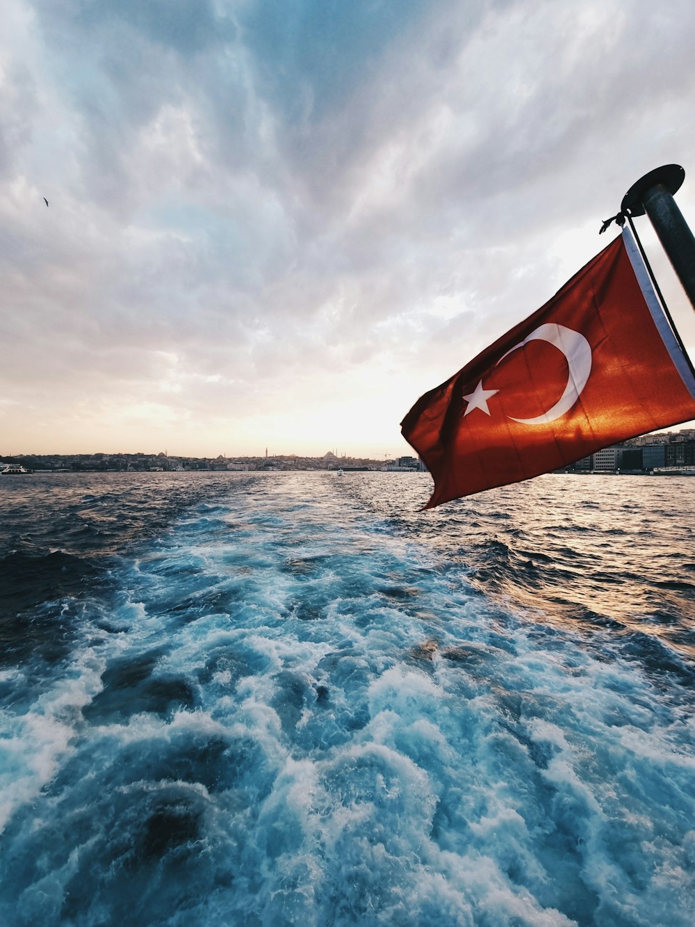 orange and white flag on body of water during daytime