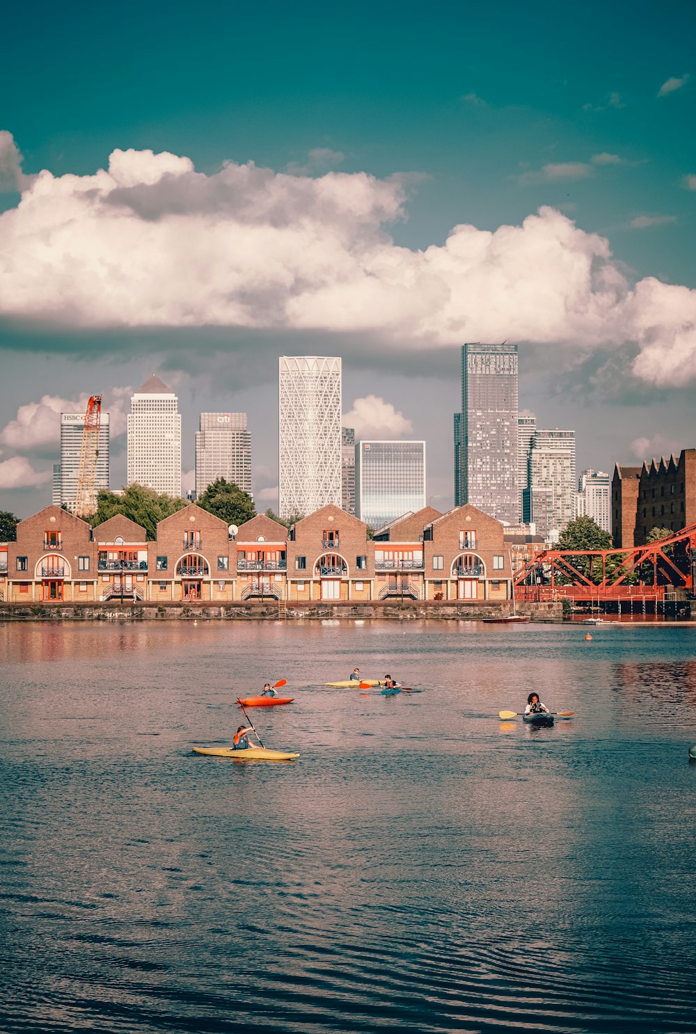 people riding on white and yellow kayak on body of water near city buildings during daytime