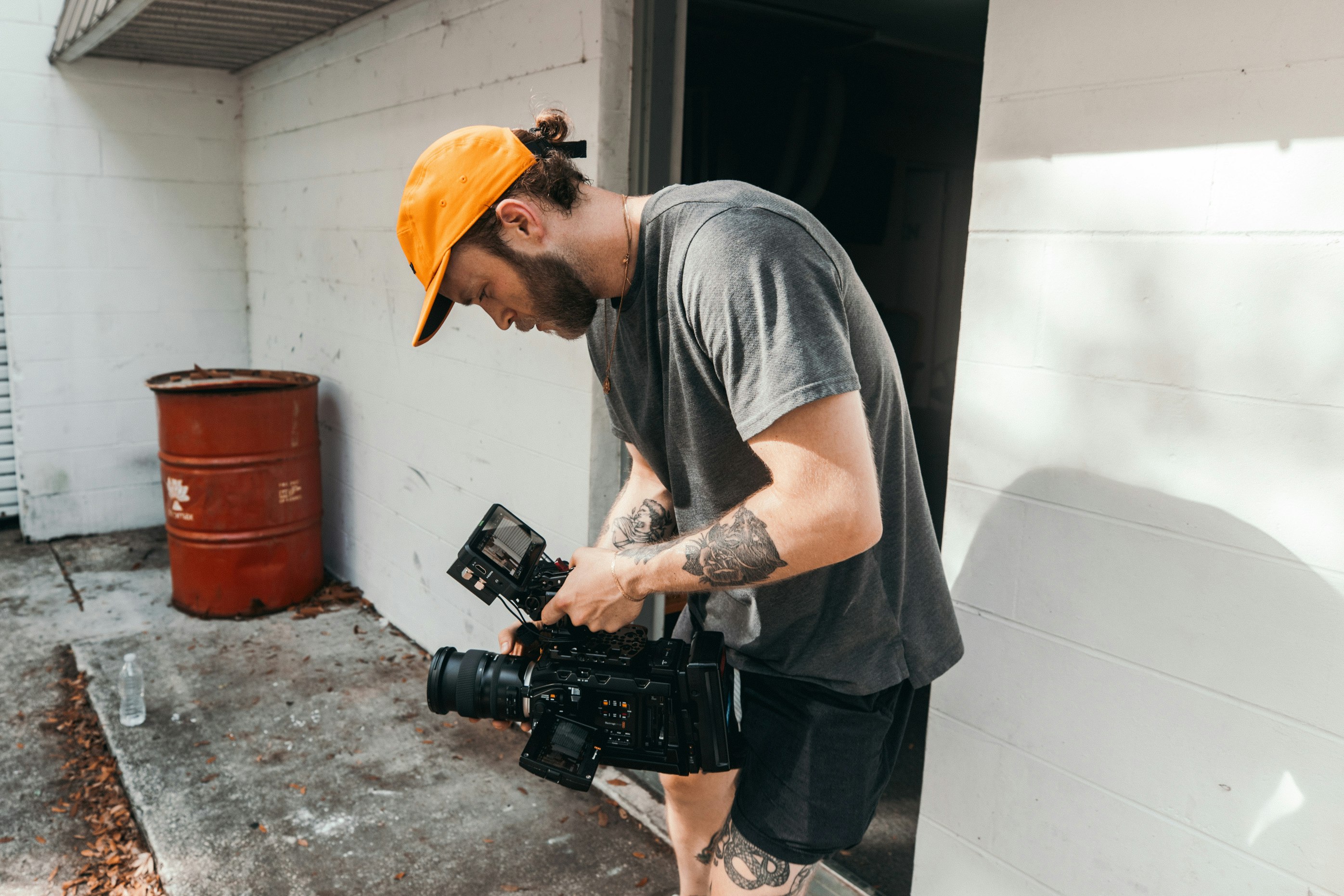 man in grey crew neck t-shirt and yellow hat holding black dslr camera