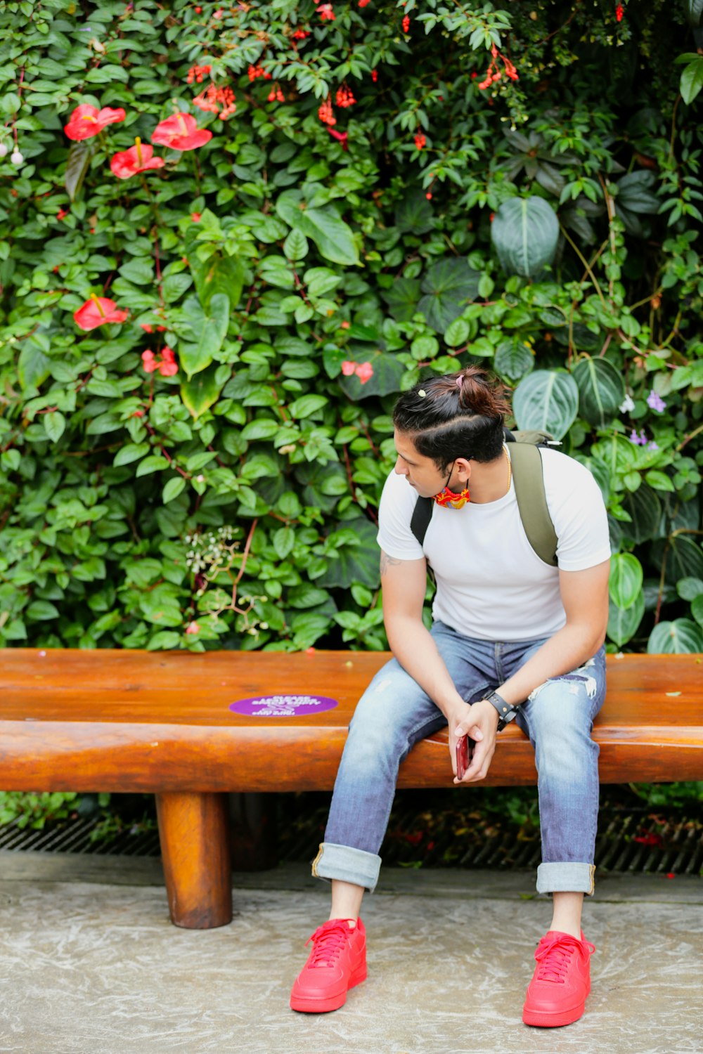 woman in white t-shirt and gray denim jeans sitting on brown wooden bench