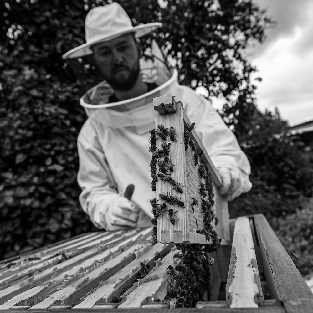 man in white long sleeve shirt and white hat holding brown wooden board