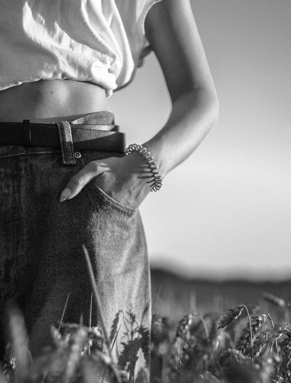 grayscale photo of woman in crop top and denim jeans