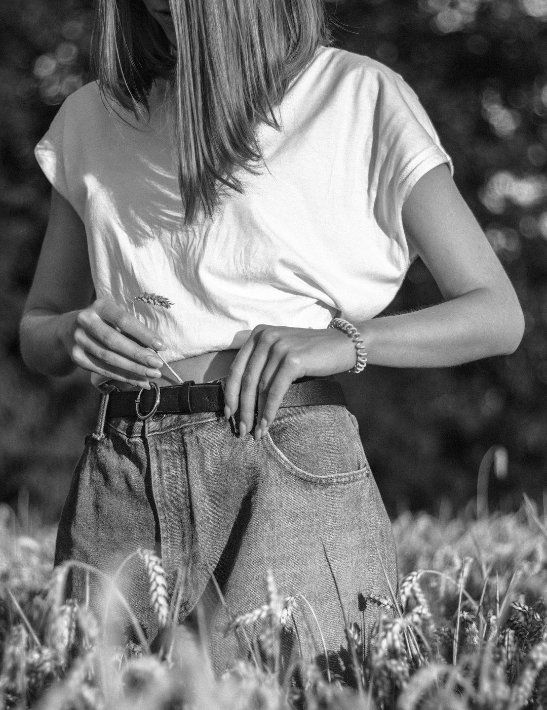 woman in white t-shirt and blue denim daisy dukes standing on grass field