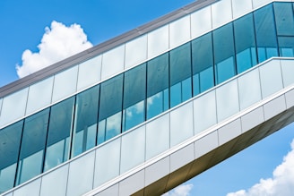 A modern architectural building with large glass windows reflecting the sky.