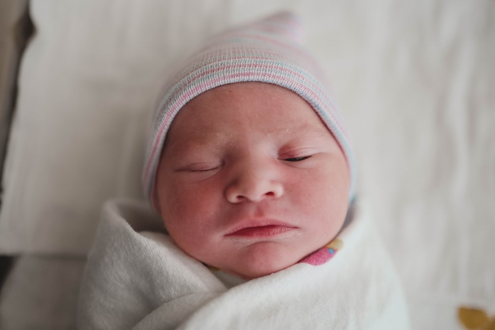 baby in white and pink knit cap