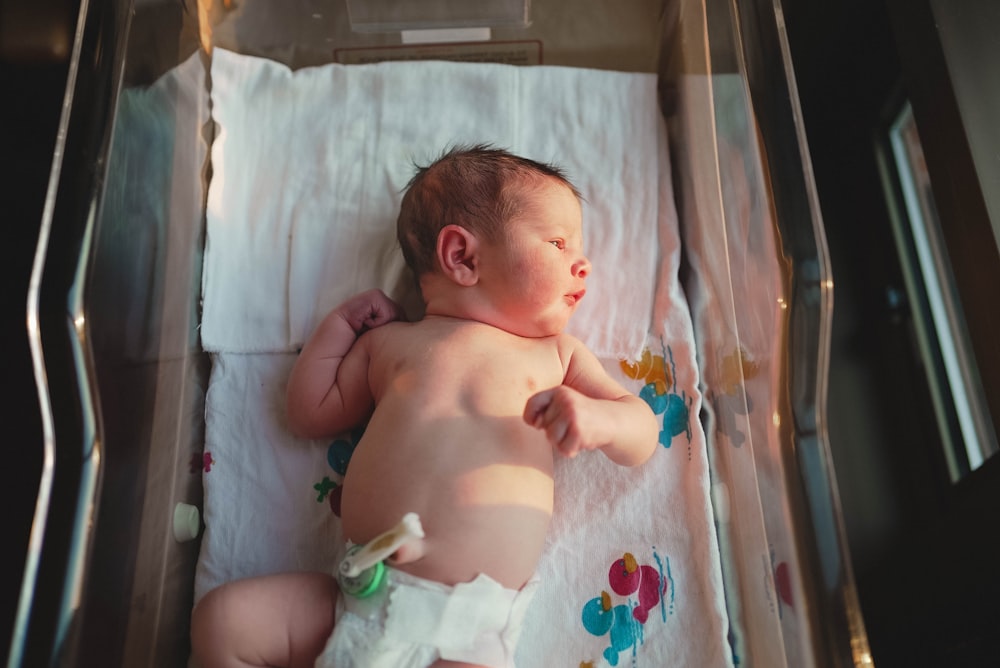 baby lying on white bed