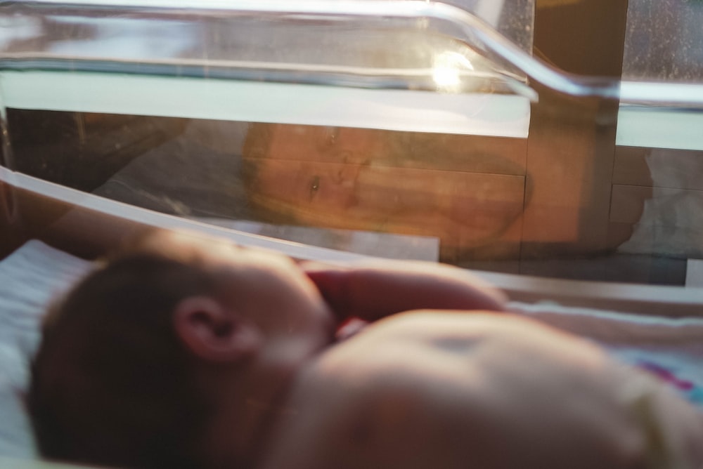 person lying on bed near brown wooden cabinet