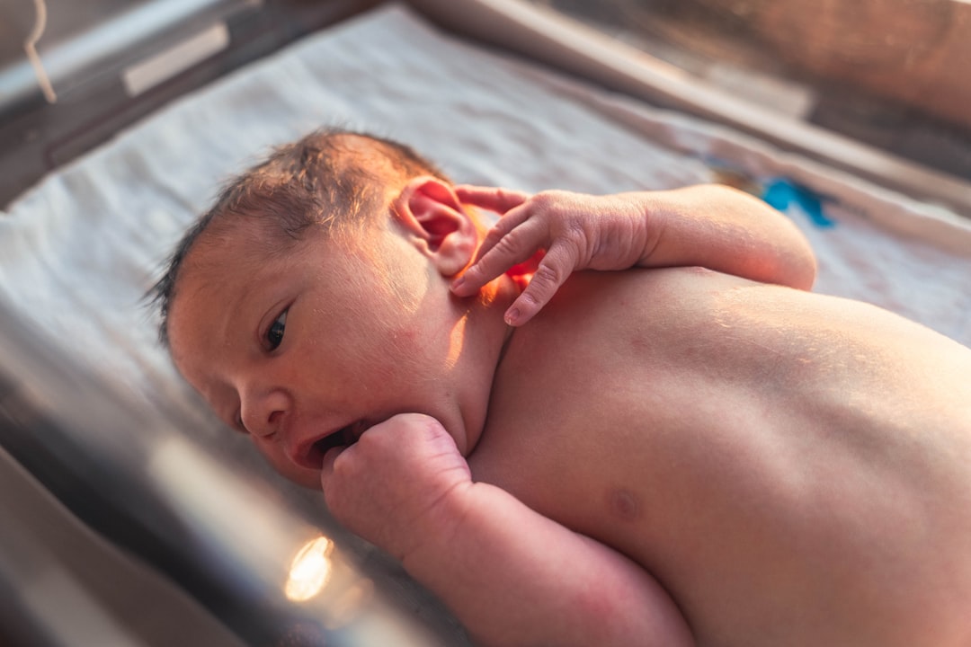 topless baby lying on blue textile