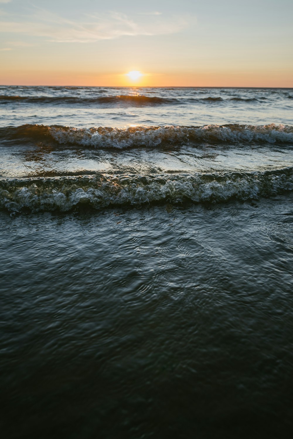 ocean waves crashing on shore during sunset