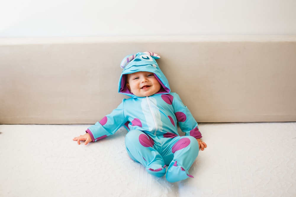 baby in pink and blue hoodie and pants lying on white textile