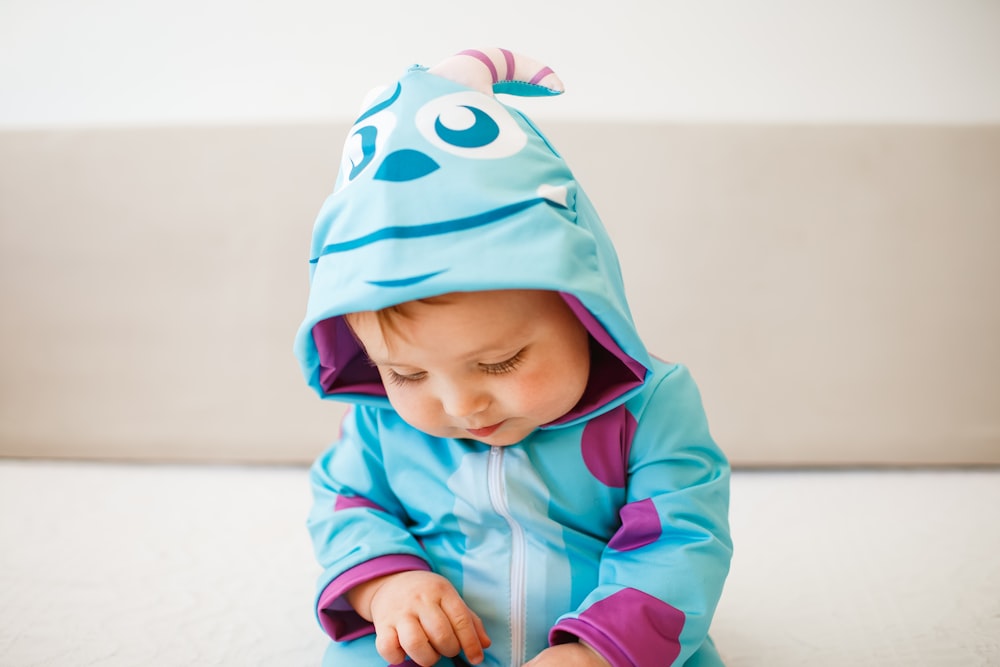baby in pink hoodie and blue and white hat