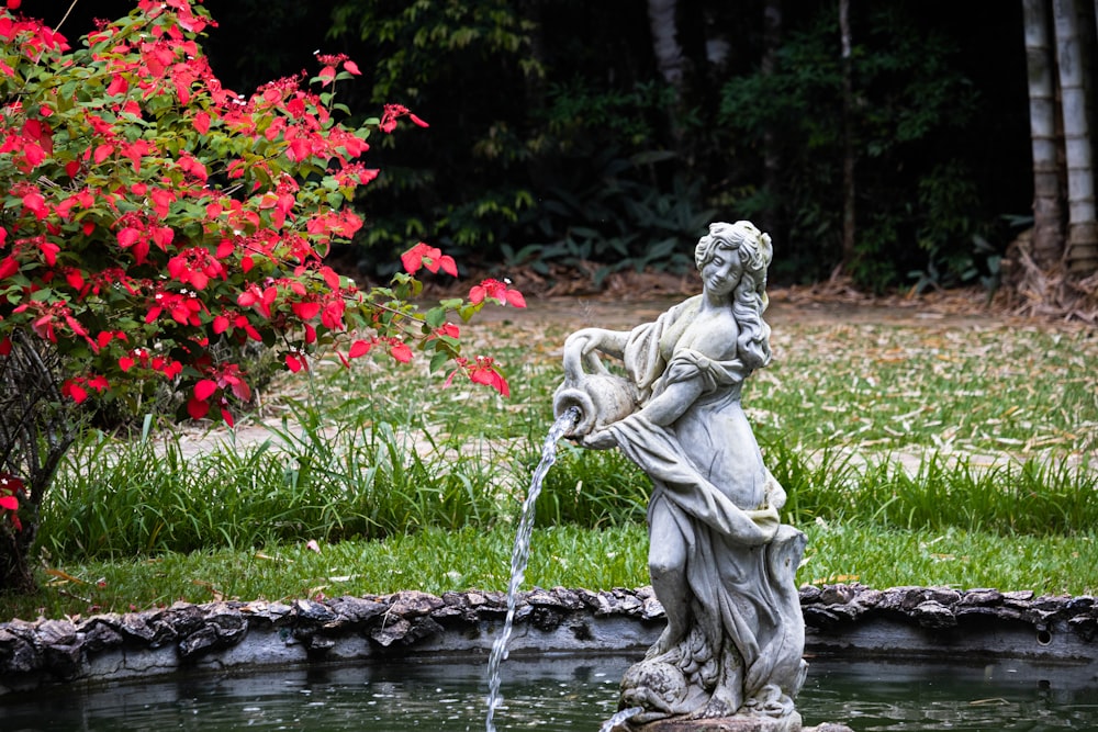 woman in dress statue near red flowers during daytime