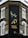 The corner of a brick building features a large, vertical sign with elegant writing in both English and another script, reading 'Persian Kitchen'. Above the text, an artistic illustration shows two birds perched on a branch with pomegranates. The building is located at the intersection of Bonchurch Road and Portobello Road.