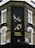 The corner of a brick building features a large, vertical sign with elegant writing in both English and another script, reading 'Persian Kitchen'. Above the text, an artistic illustration shows two birds perched on a branch with pomegranates. The building is located at the intersection of Bonchurch Road and Portobello Road.