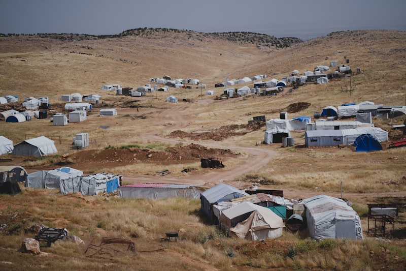 Tents and makeshift shelters at a displacement camp on arid terrain
