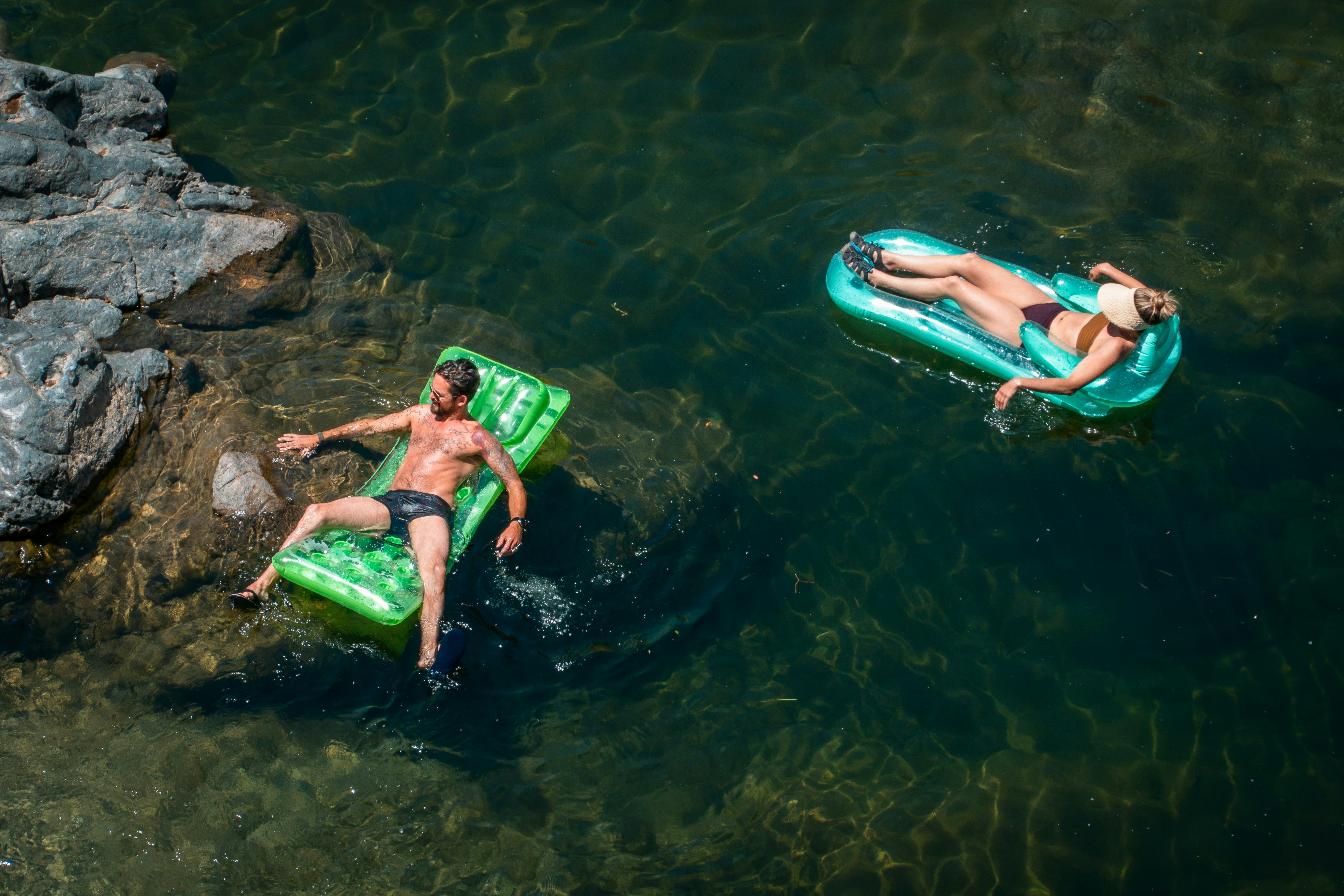 2 women in green and black bikini lying on green inflatable float on water during daytime