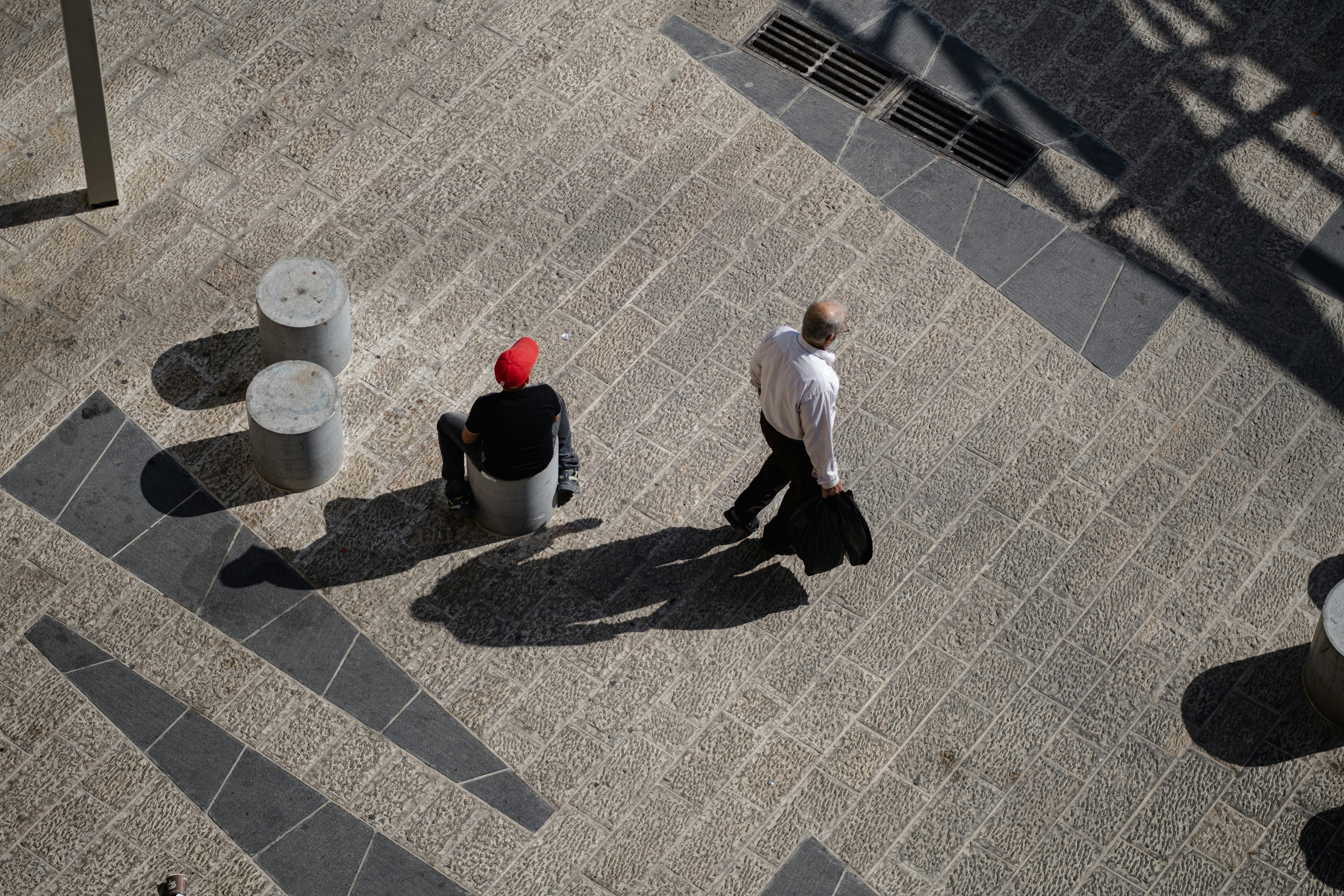 Man in white dress shirt and black pants sitting on white plastic trash bin