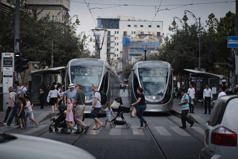 people walking on sidewalk near white train during daytime