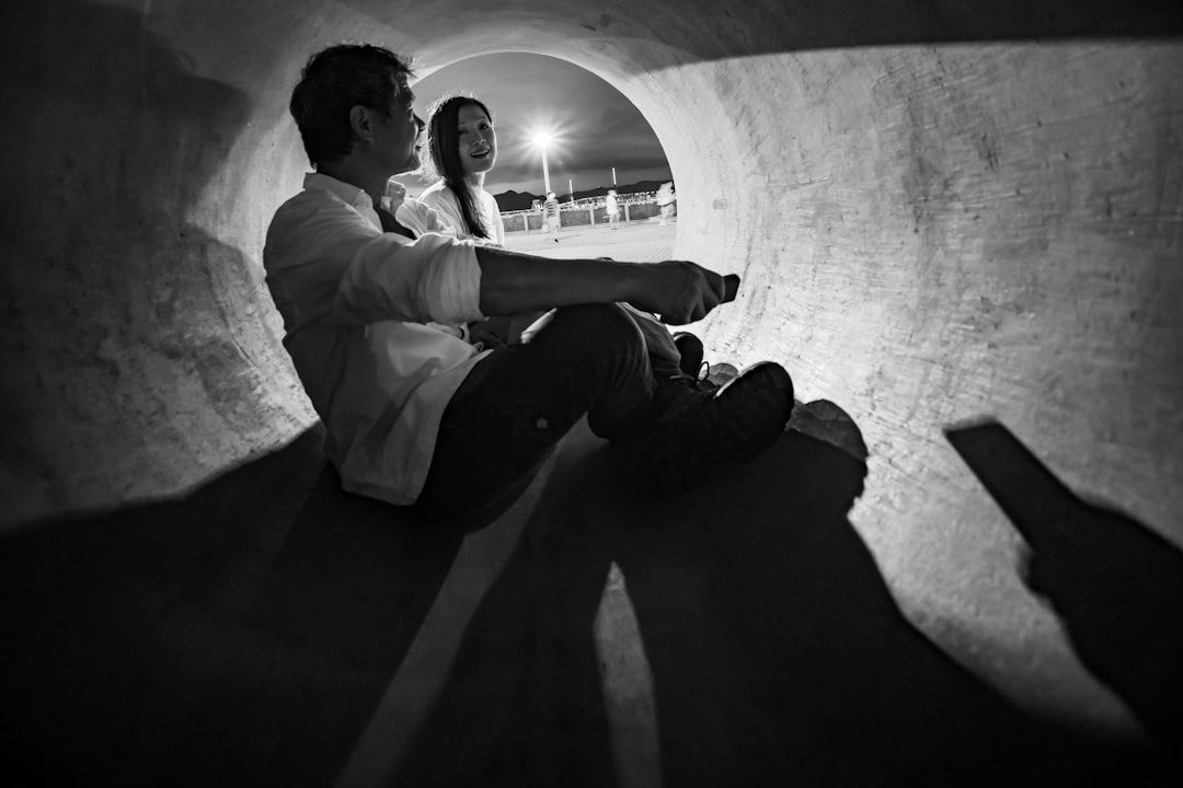 man in white dress shirt and black pants sitting on concrete wall