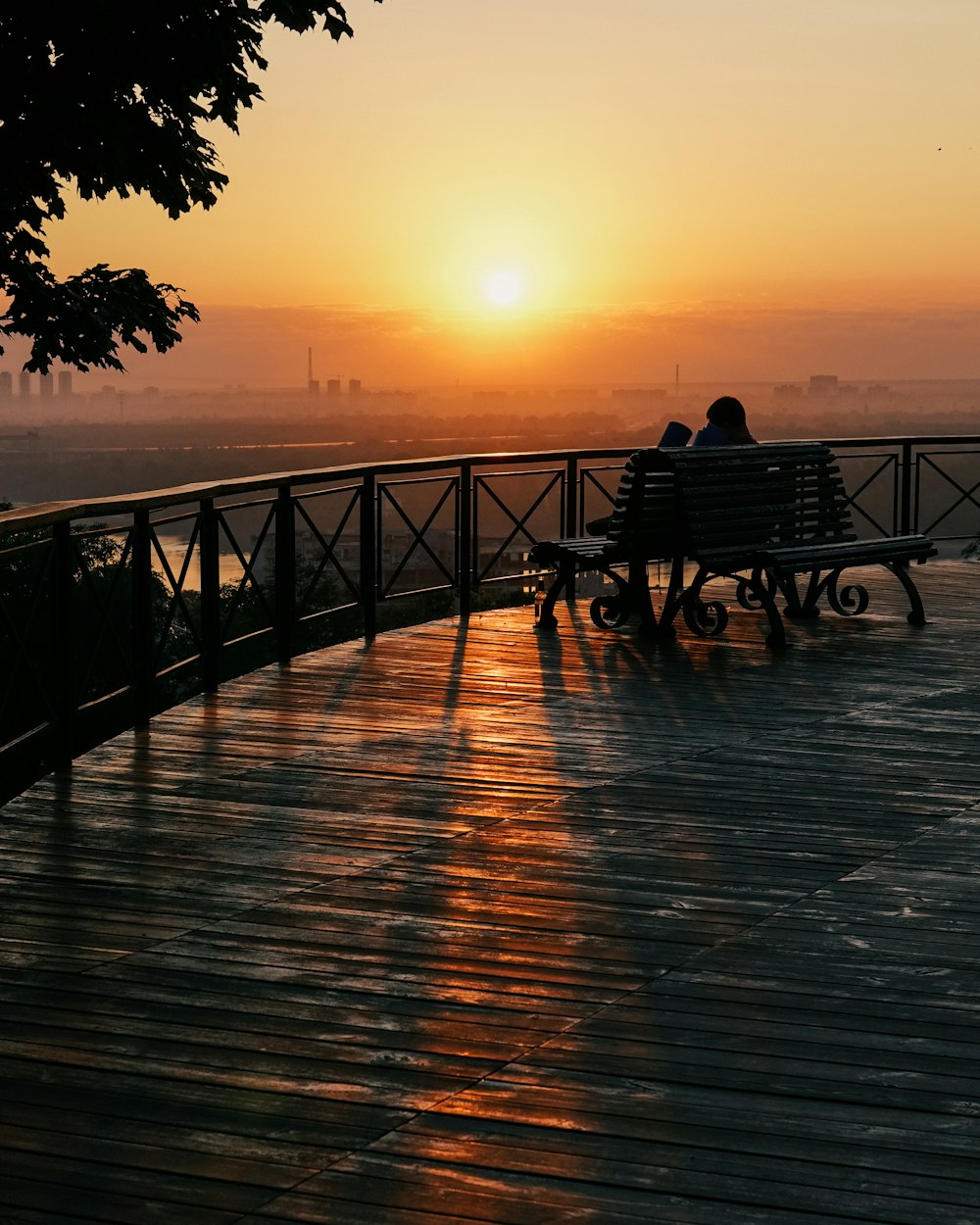 Hombre y mujer sentados en el banco en el muelle durante la puesta del sol