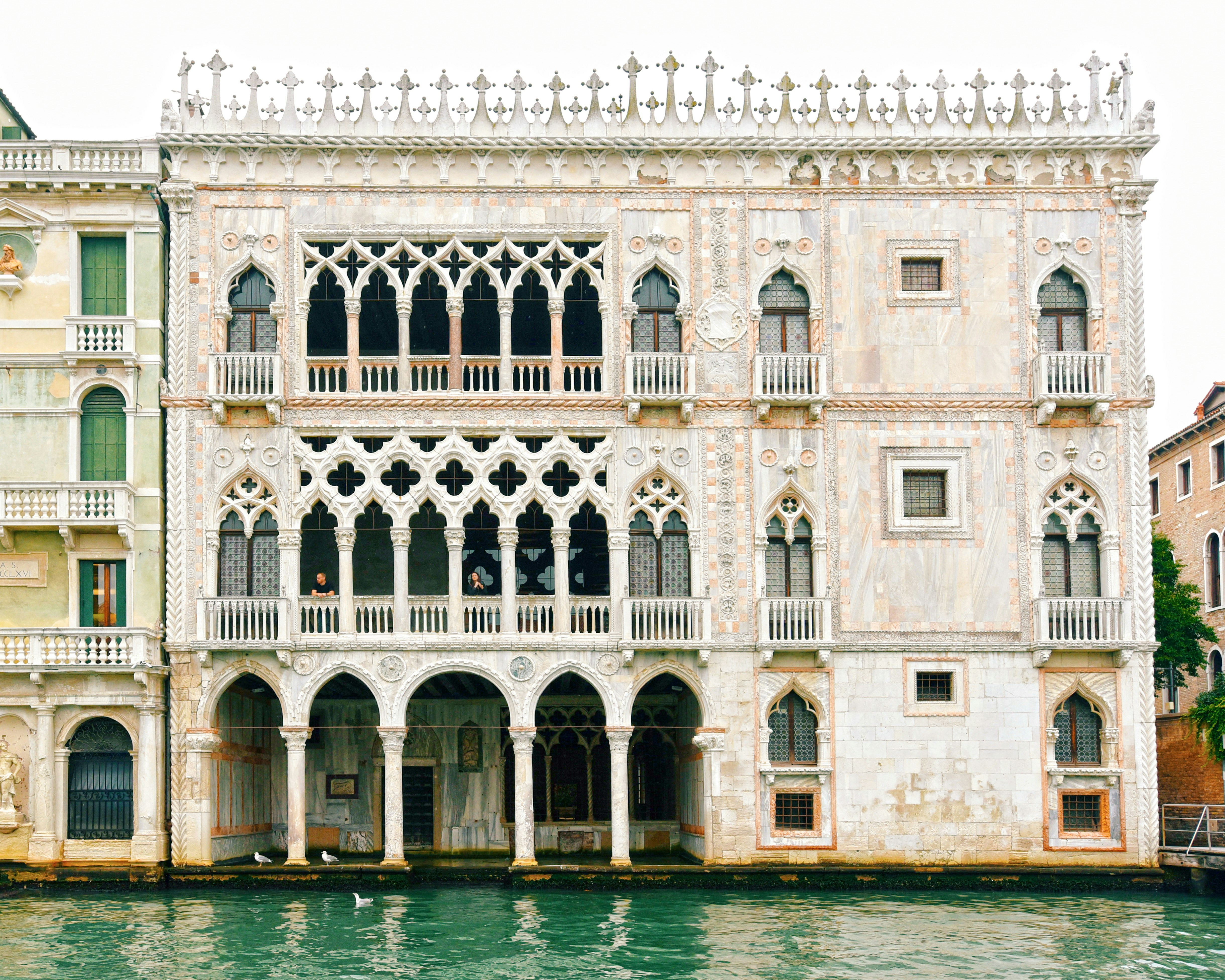 edificio in cemento bianco vicino a uno specchio d'acqua durante il giorno