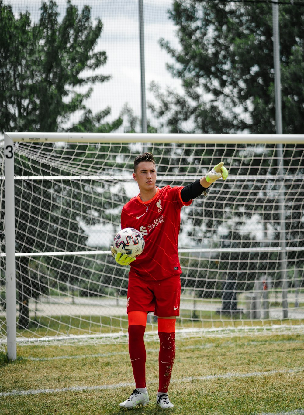 boy in red and white soccer jersey holding soccer ball