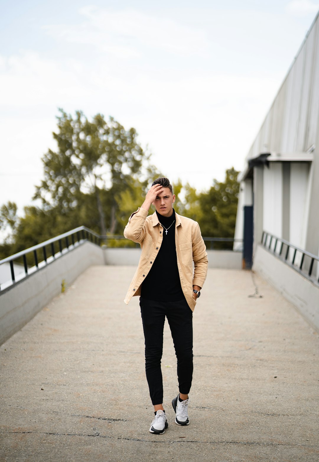 woman in brown coat and black pants standing on gray concrete pathway during daytime