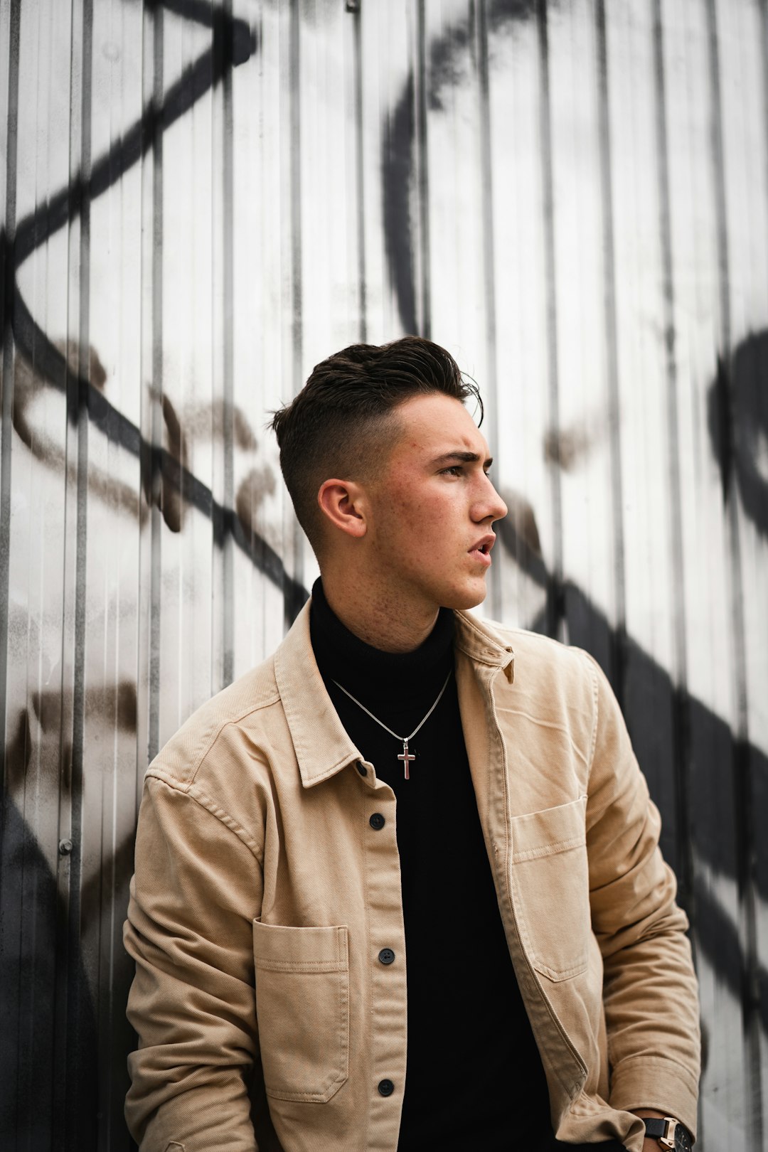 man in brown coat standing near gray wall