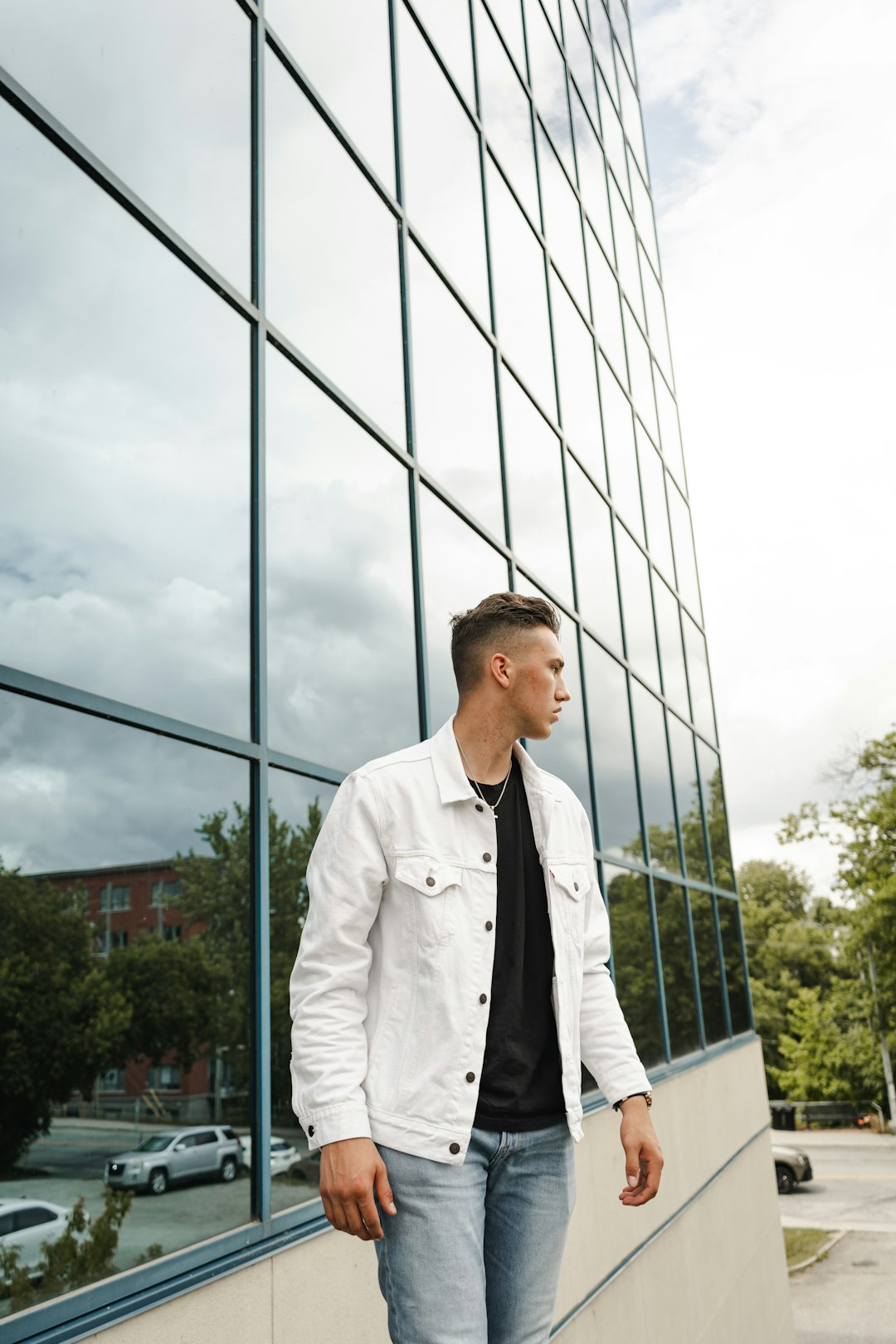 man in white coat standing near glass building during daytime