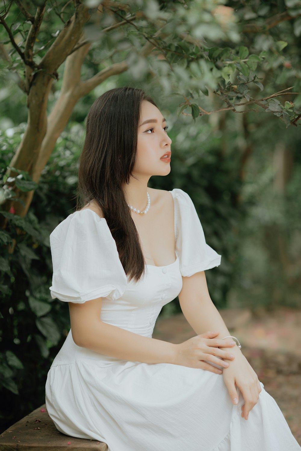 woman in white dress sitting on tree branch