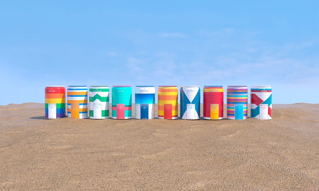 blue red and green plastic containers on brown sand under blue sky during daytime