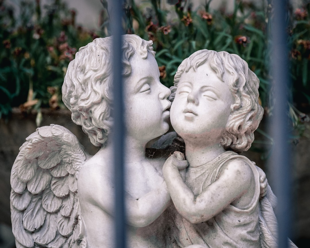 angel statue near red flowers