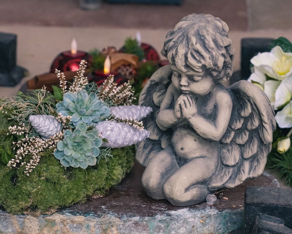 gray angel figurine beside red rose