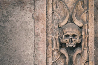 A close-up of a rustic skull sculpture with intricate carvings and a weathered finish, perfect for edgy home decor.