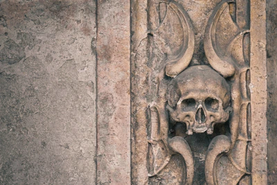 A close-up of a rustic skull sculpture with intricate carvings and a weathered finish, perfect for edgy home decor.
