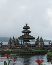 Traditional Balinese temple surrounded by vibrant flowers and ancient stone carvings.