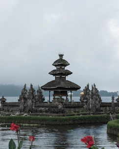 Traditional Balinese temple surrounded by vibrant flowers and ancient stone carvings.