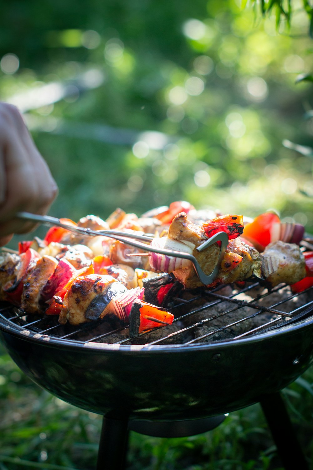 personne tenant une fourchette et un couteau en train de trancher de la viande sur un gril noir