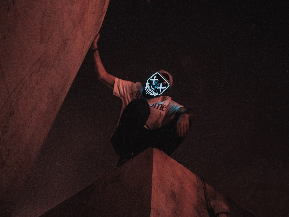 Homme en t-shirt noir et jean bleu assis sur des escaliers en béton brun