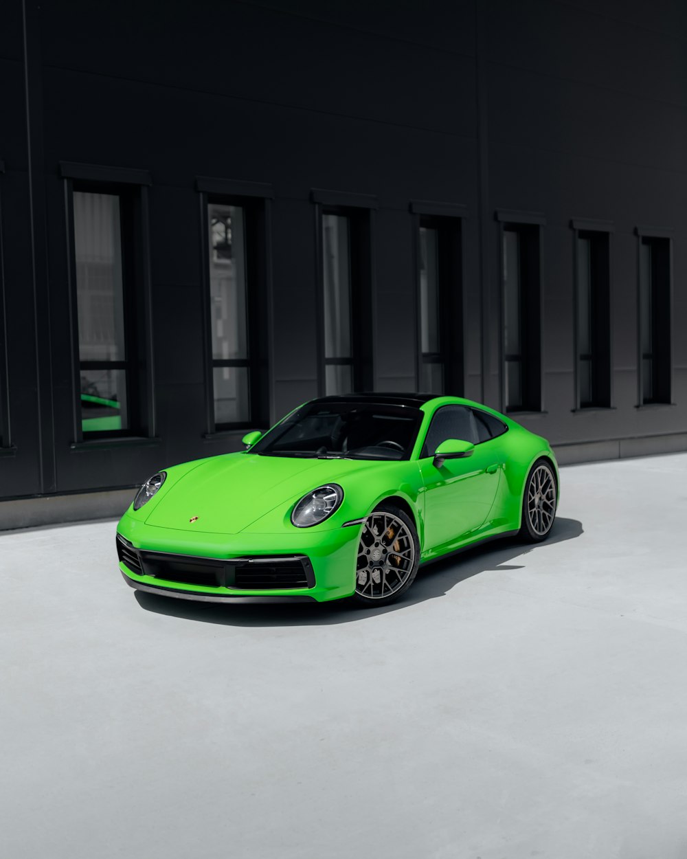 green porsche 911 parked in front of building
