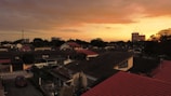 A beautiful sunset over a neighborhood with various roof styles.