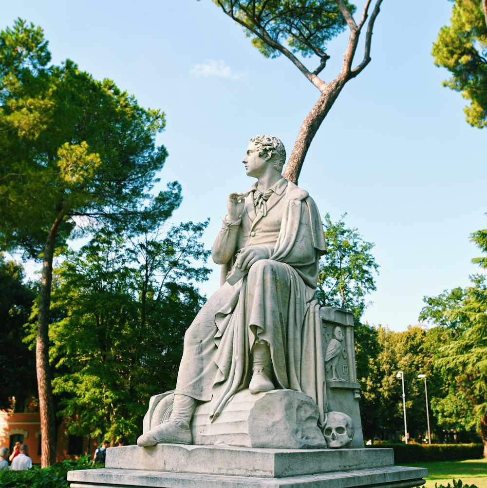 woman in dress statue near green trees during daytime