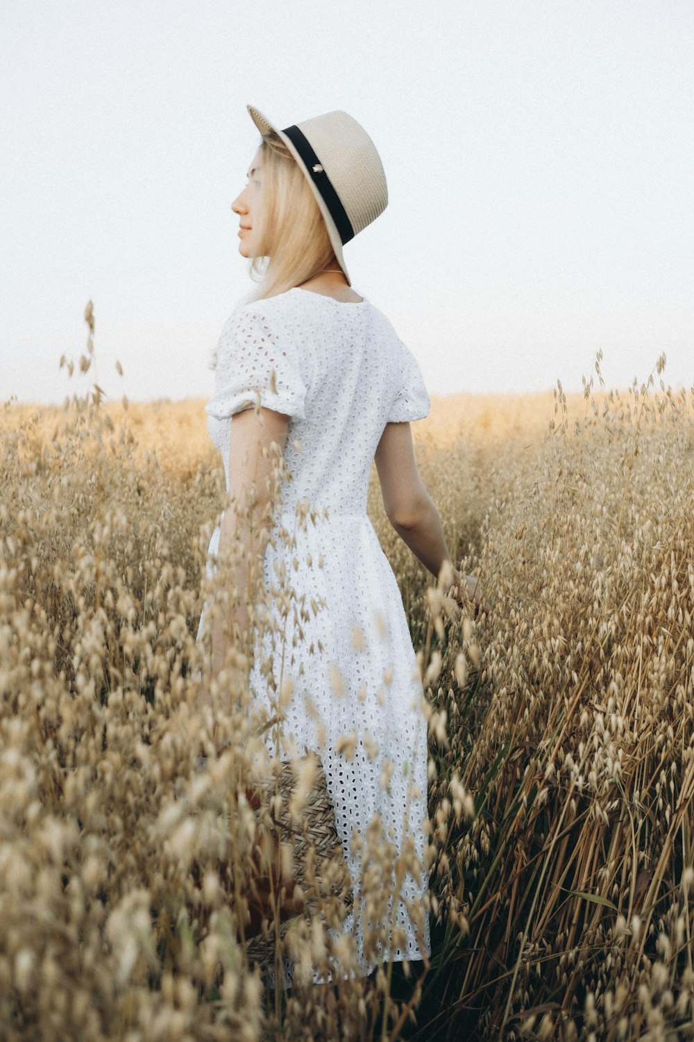 woman in white floral dress standing on brown wheat field during daytime