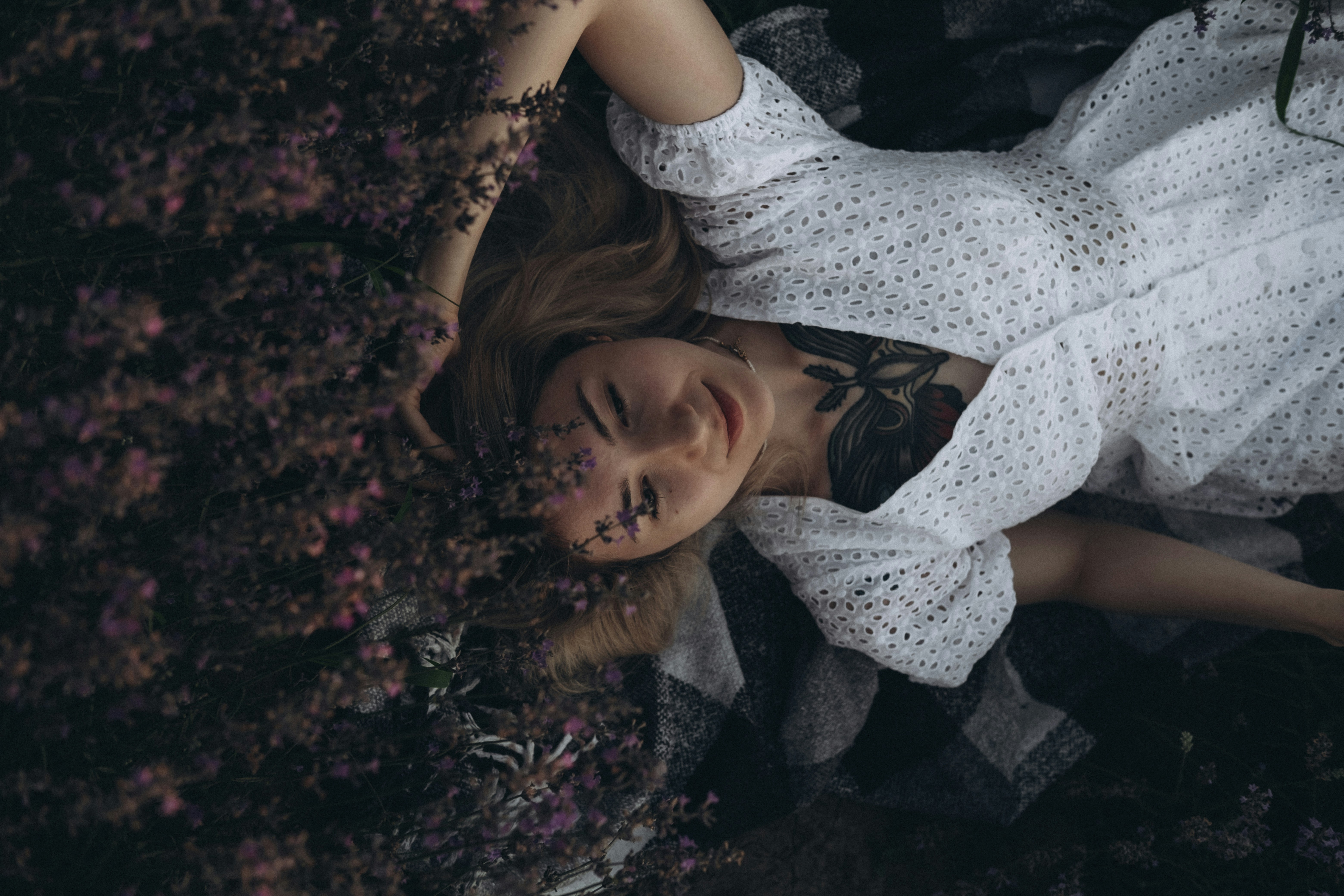 woman in white and black floral dress lying on red and black leaves