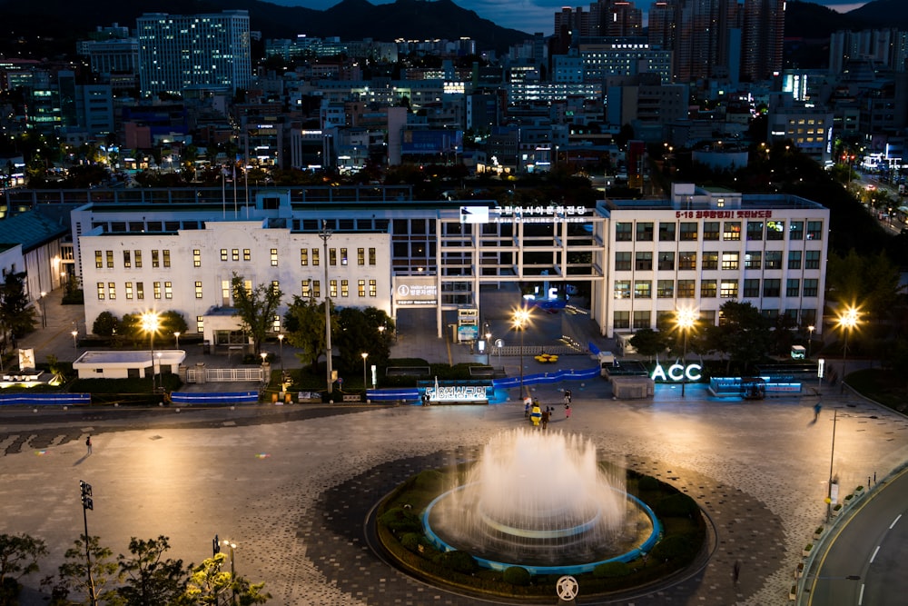 water fountain in the middle of city buildings during night time
