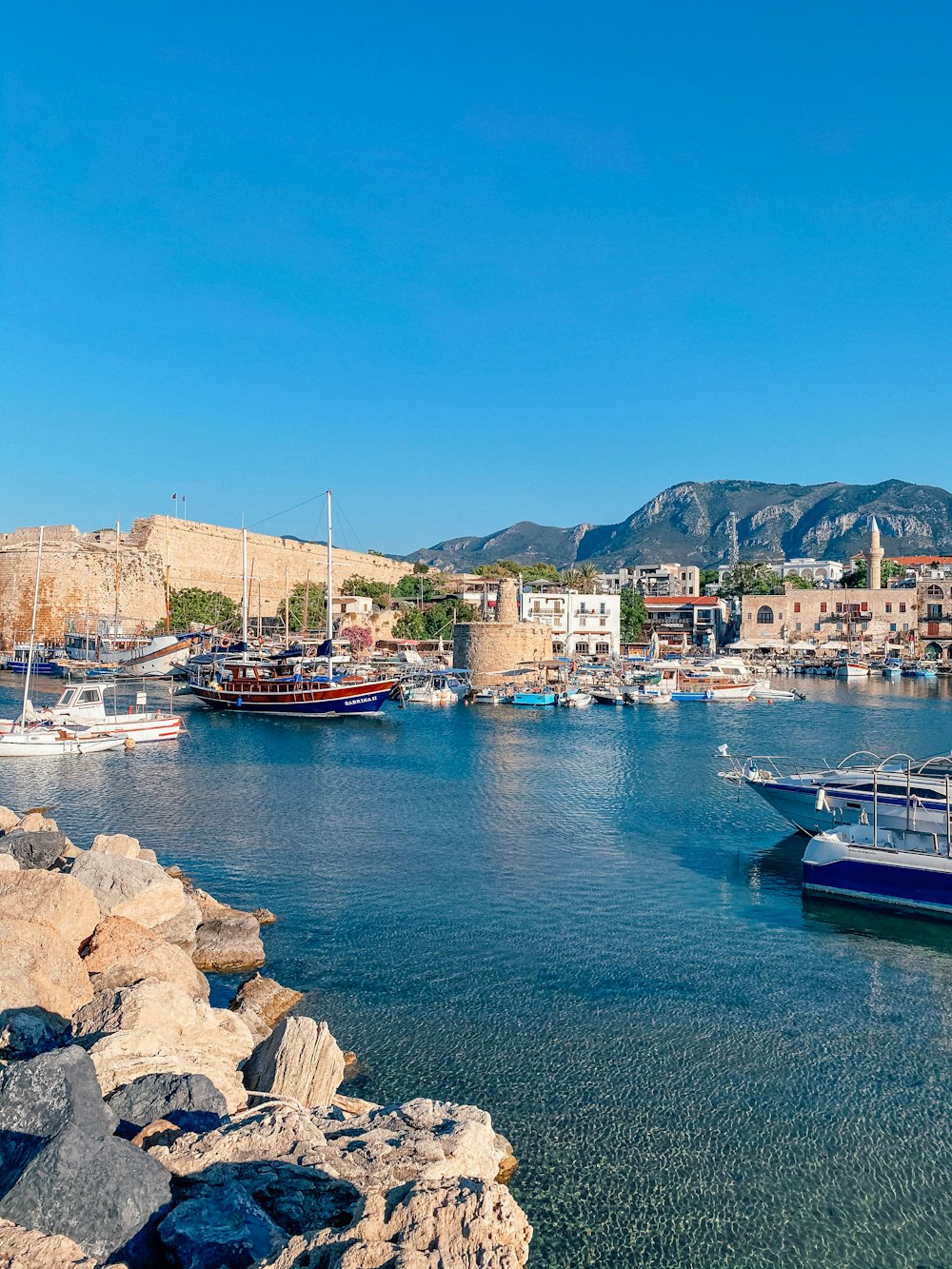 Barca rossa e bianca sul mare vicino a rocce marroni durante il giorno